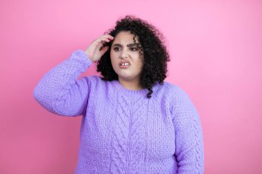 Soyutlanmış pembe arka plan karışıklığı üzerine gündelik kazak giyen genç ve güzel bir kadın soru sormayı merak ediyor. Şüpheyle karışık, kafa kafaya düşünerek.