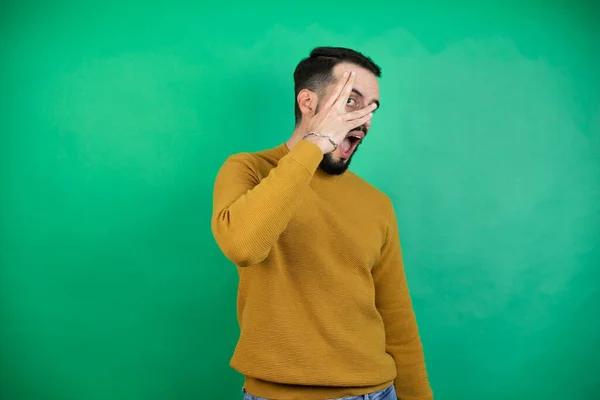 Bonito Homem Vestindo Roupas Casuais Sobre Fundo Verde Isolado Espreitando — Fotografia de Stock