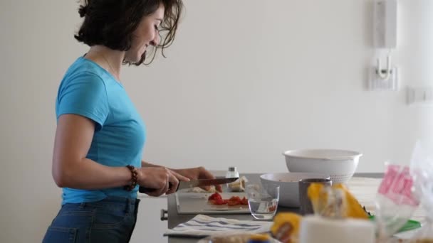 Νεαρή όμορφη Ιταλίδα γυναίκα κόβει φρέσκιες ντομάτες ενώ χορεύει — Αρχείο Βίντεο