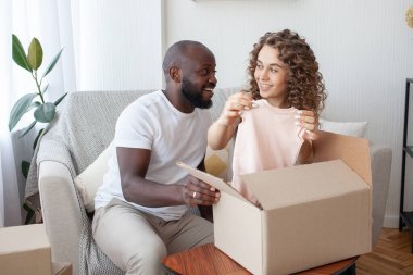 Genç evli çiftin ilk yerleşimi. Kanepede oturan mutlu hamile anne, doğmamış kızı ve hızlı doğum için güzel kıyafetlerin keyfini çıkarıyor. Hamilelik ve online alışveriş kavramı.