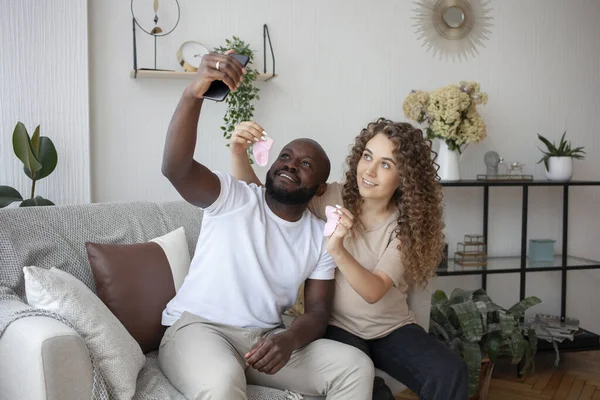 非洲裔美国人的丈夫和一个漂亮的怀孕女孩在家做自己与婴儿袜子送给他们的亲戚 人和怀孕概念 — 图库照片