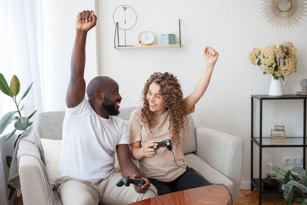 积极地休息一对年轻漂亮的夫妇 非洲裔美国人和准妈妈庆祝拉上电玩游戏 举起双手 握着操纵杆 家庭和怀孕概念 — 图库照片