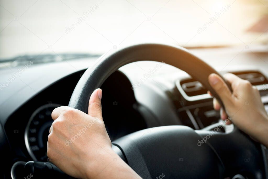 A woman's hand holding a car steering wheel,represents the correct car steering wheel. In order to prevent accidents. Show driving safe step.