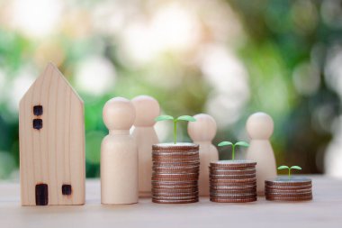 Ahşap bir ev, bozuk paralarla dolu tahta bebekler, gelecek için konsept planı, umut, para yatırımı, bokeh arkaplan sigortası göstermek için üste büyüyen bitki..