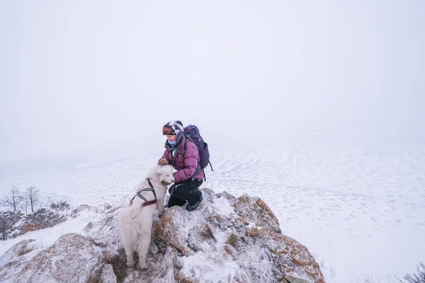 白い犬と凍った海の上の崖の端に立って観光の女性の肖像画 シベリアの冬のハイキング — ストック写真