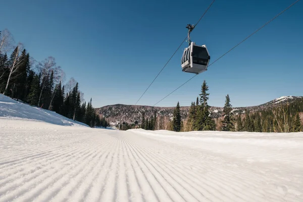 Gondola lift in the ski resort on steep slope groomed and prepared for skiing