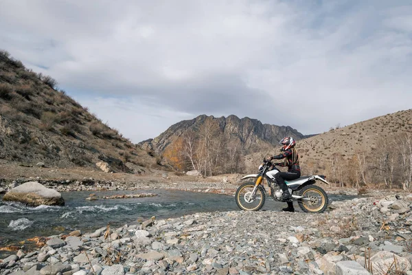 河边秀丽的高山上骑越野车的女摩托车手 — 图库照片
