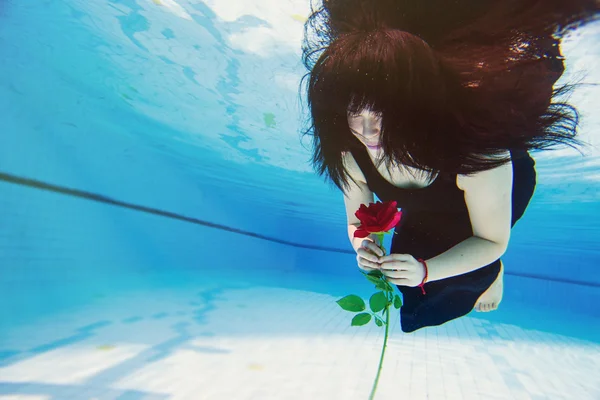 Asiatische Frau unter dem Wasser hält eine Rose — Stockfoto