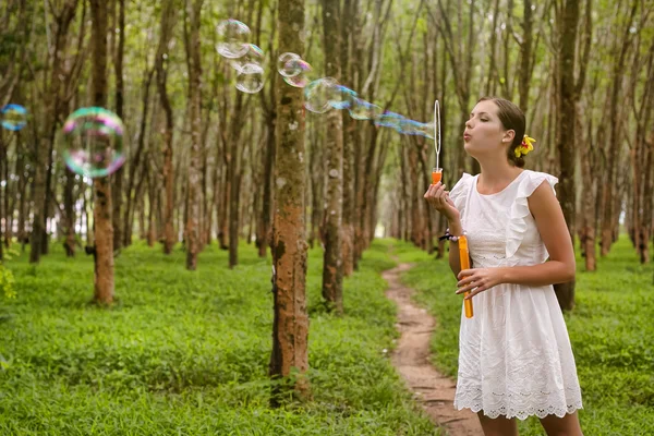 Donna soffiando bolle nella foresta — Foto Stock