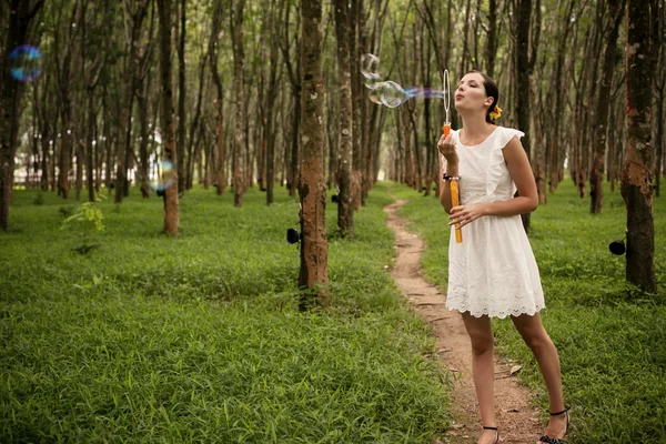 Žena foukání bublin v lese — Stock fotografie