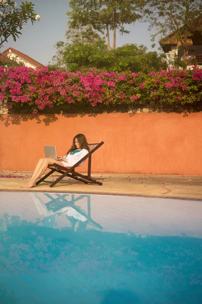 Mulher trabalhando com laptop perto da piscina — Fotografia de Stock