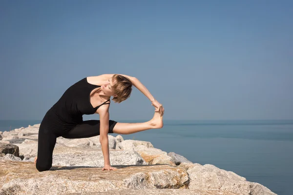 Woman practicing yoga at seashore — Stock Photo, Image