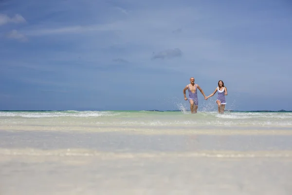 Happy retro couple running on the sea — Stock Photo, Image