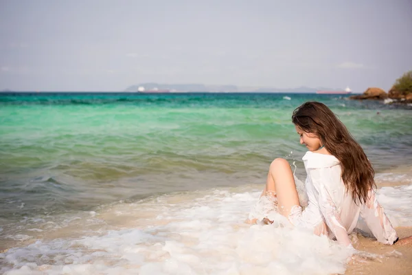 Woman sitting in a waves on the beach — Stock Photo, Image