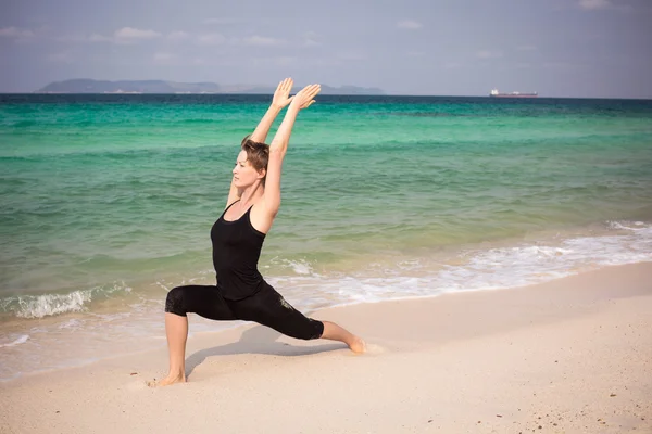 Vrouw praktizerende yoga op het strand — Stockfoto