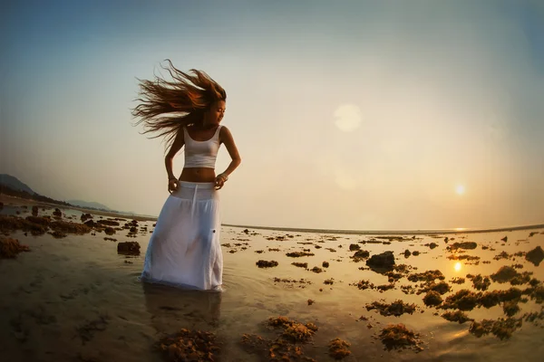 Mulher está dançando na praia ao pôr do sol — Fotografia de Stock