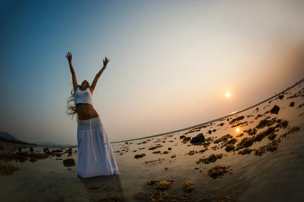 woman is dancing on the beach at sunset