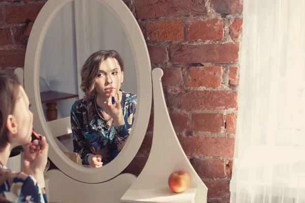 woman make up her lips and looking to the mirror