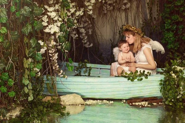 Mãe segurando e beijando o bebê em um barco — Fotografia de Stock