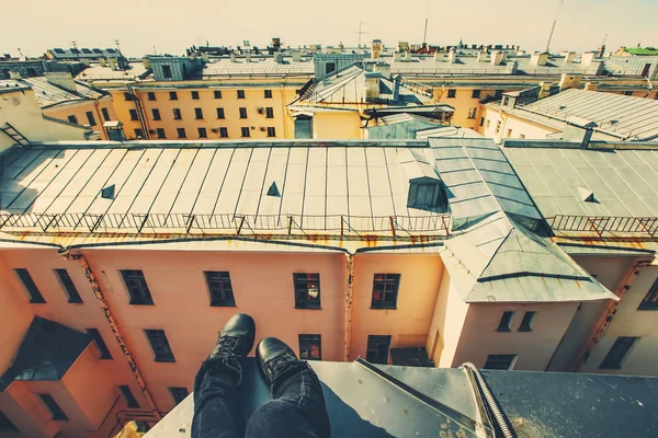 Pernas da pessoa sentada no telhado — Fotografia de Stock