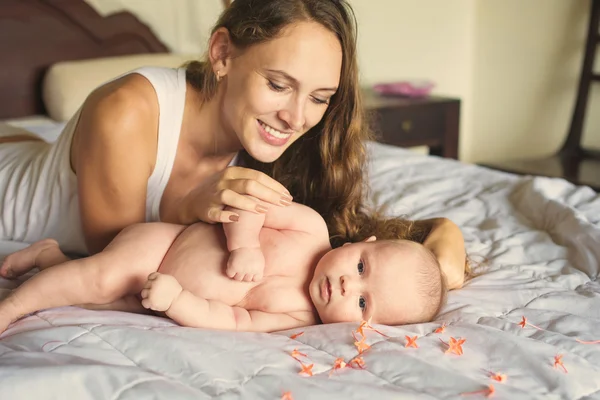 Мать с новорожденным ребенком просыпается на кровати — стоковое фото