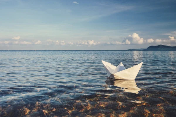 Origami paper sailboat sailing on water
