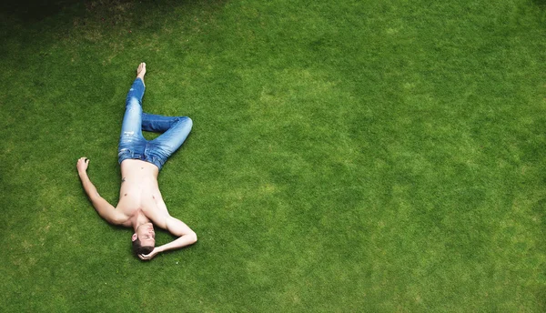 Uomo rilassante sdraiato sull'erba verde — Foto Stock
