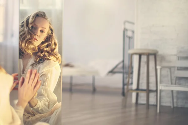 Femme regardant vers le miroir dans la chambre lumineuse — Photo