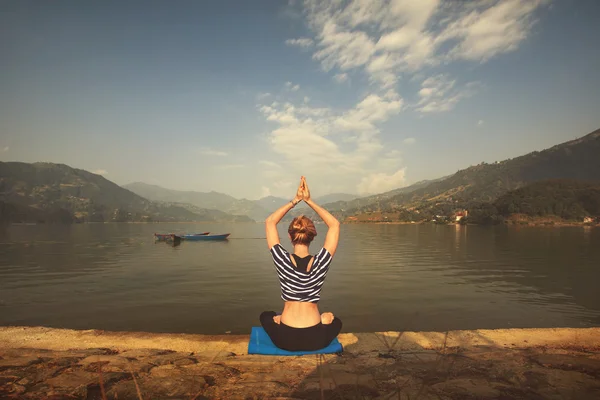 Young female practicing yoga on the shore of mountain lake — Stock Photo, Image