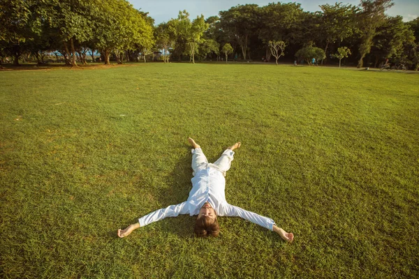 Homme d'affaires en costume blanc en vacances couché sur l'herbe verte — Photo