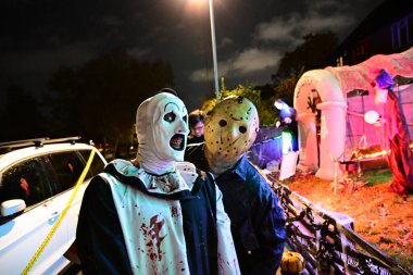 Korku kostümü giymiş iki kişi gece dekore edilmiş bahçede poz veriyor. Yüksek kalite fotoğraf