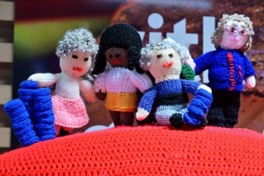 Dört tane el yapımı bebek, kırmızı örgü üzerine yerleştirilmiş ve eşsiz giyim tarzları var. Yüksek kalite fotoğraf