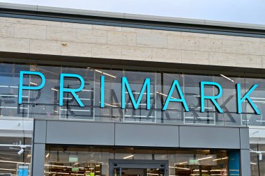 Turkuaz logo, cam cephe, marka ve görünür perakende vitrinleri olan modern Primark mağaza önü.