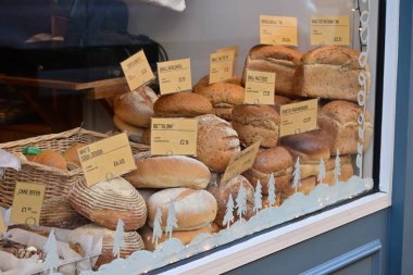 Festivalsel kış temalı mağaza vitrininde düzenlenmiş etiketli zanaatkar ekmeklerinin çeşitliliği.