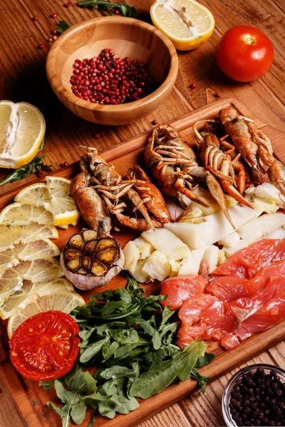 Раков, филе красной и белой пангасы на деревянной тарелке — стоковое фото