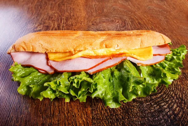 Бутерброд зі свіжого багета на дерев'яному фоні — стокове фото