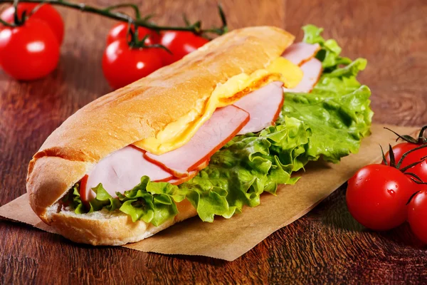 Бутерброд зі свіжого багета на дерев'яному фоні — стокове фото