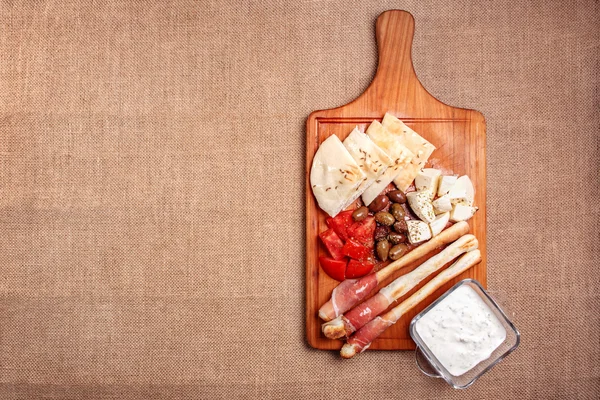 Bread sticks with prosciutto Cured Meat on a wooden cutting boar