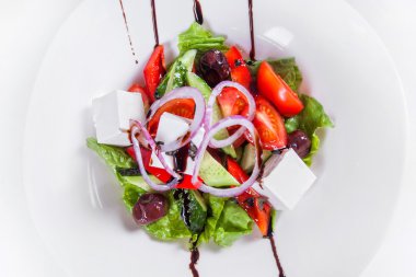 Taze sebze, beyaz peynir, zeytin ve sos ile Yunan salatası. Beyaz arka planda yalıtılmış çanak