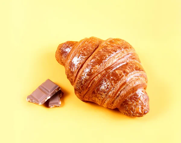 Croissant saboroso com chocolate e geléia no fundo amarelo. Pastéis e pão em uma padaria — Fotografia de Stock