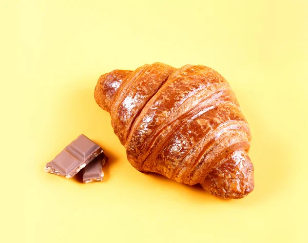 Croissant savoureux avec chocolat et confiture sur fond jaune. Pâtisseries et pain dans une boulangerie — Photo