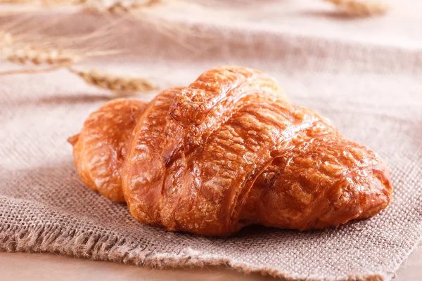 Tasty croissant with jam on rustic background with spikelets. Pastries and bread in a bakery — Stock Photo, Image