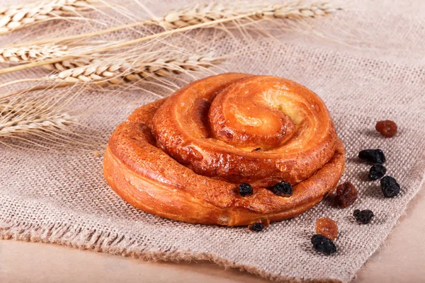 Édes zsömle mazsolát és Vaníliás krém a rusztikus háttér spikelets. Süteményeket és kenyeret egy pékség — Stock Fotó