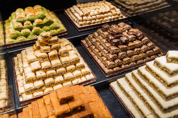 Dulces orientales en una amplia gama, baklava, delicia turca con almendras, anacardos y pistachos en platos —  Fotos de Stock