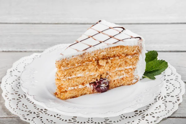 Honigkuchen mit Walnüssen und Kirschen auf Teller, auf hellem Holzgrund. Selektiver Fokus — Stockfoto