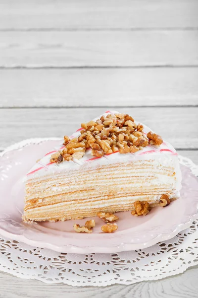 Honey cake with walnuts on plate, on a light wooden background. Selective focus — Stock Photo, Image