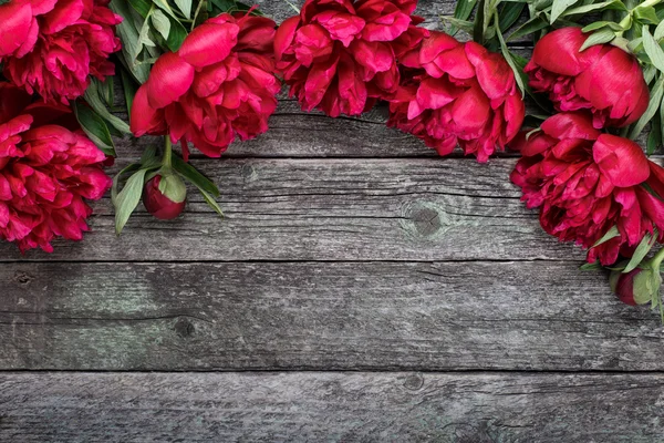 Floral frame met roze pioenrozen bloemen op rustieke houten achtergrond. Selectieve aandacht, plaats voor tekst, bovenaanzicht — Stockfoto