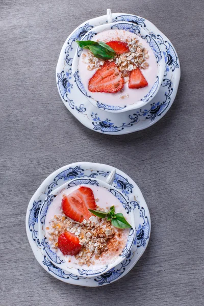 I cereali sani con fragole e yogurt decorano con zecca in ciotole di ceramica su tavolo di legno, vista dall'alto. Granola, muesli — Foto Stock