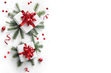 Noel ağacı dalları, kırmızı kurdeleli hediye kutuları, kırmızı süslemeler, parıltılar ve beyaz arka planda konfeti. Noel ve yeni yıl tebrik kartı, kış tatili. Düz konum, üst görünüm, çerçeve