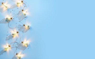 Mavi arka planda gümüş süslemeli mutlu noel çelenkleri, köknar dalları, konfeti, bokeh, sim. Noel ve yeni yıl tebrik kartı, kış tatili. Düz yatış, üst görünüm
